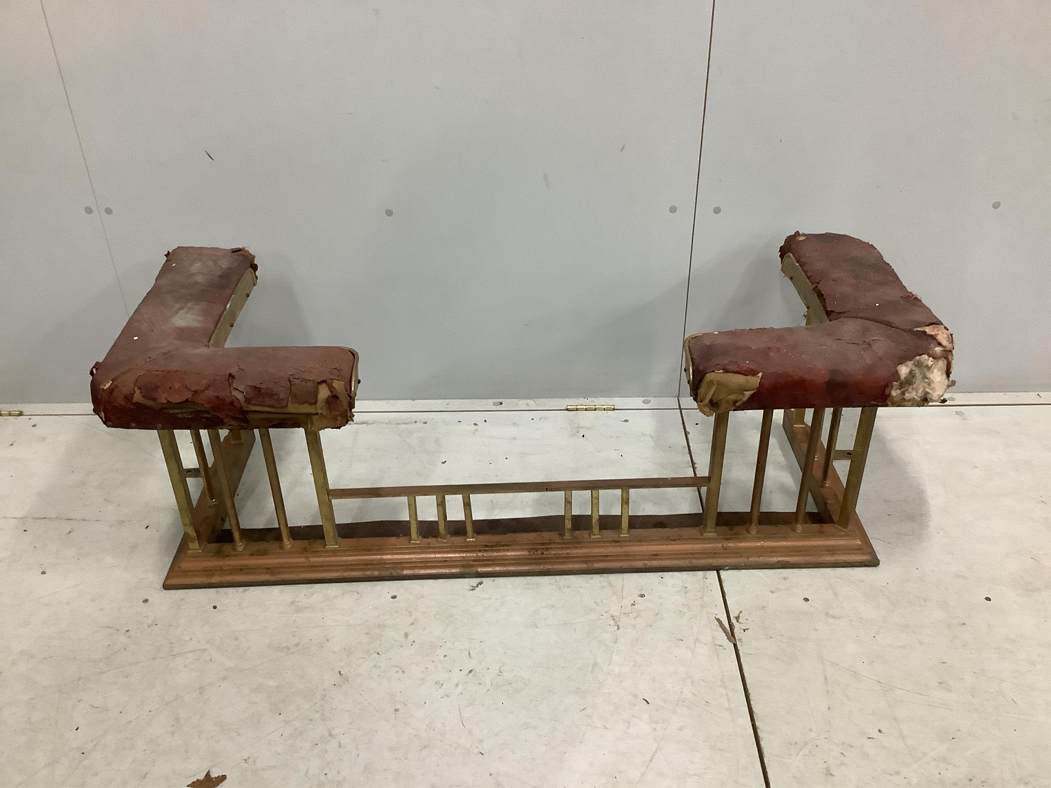 An Edwardian iron and brass club fender, width 128cm, depth 50cm, height 44cm. Condition - poor and in need of restoration, red leather seats will need replacing, metalwork tarnished, rear right side cut to accommodate a